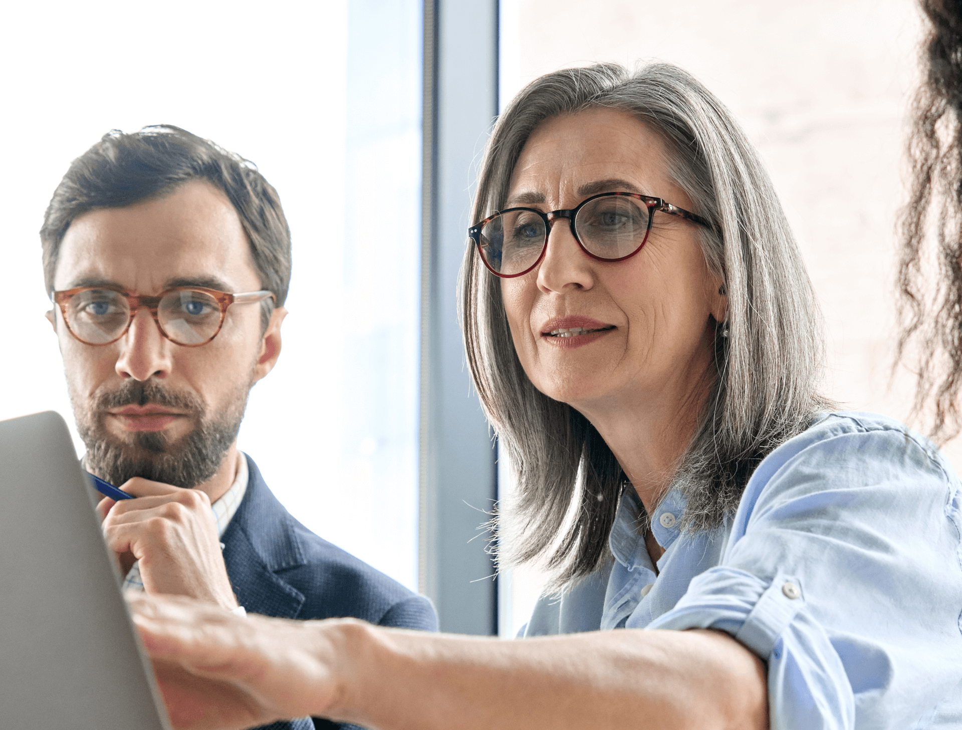 Women wearing glasses pointing a screen and young man looking on