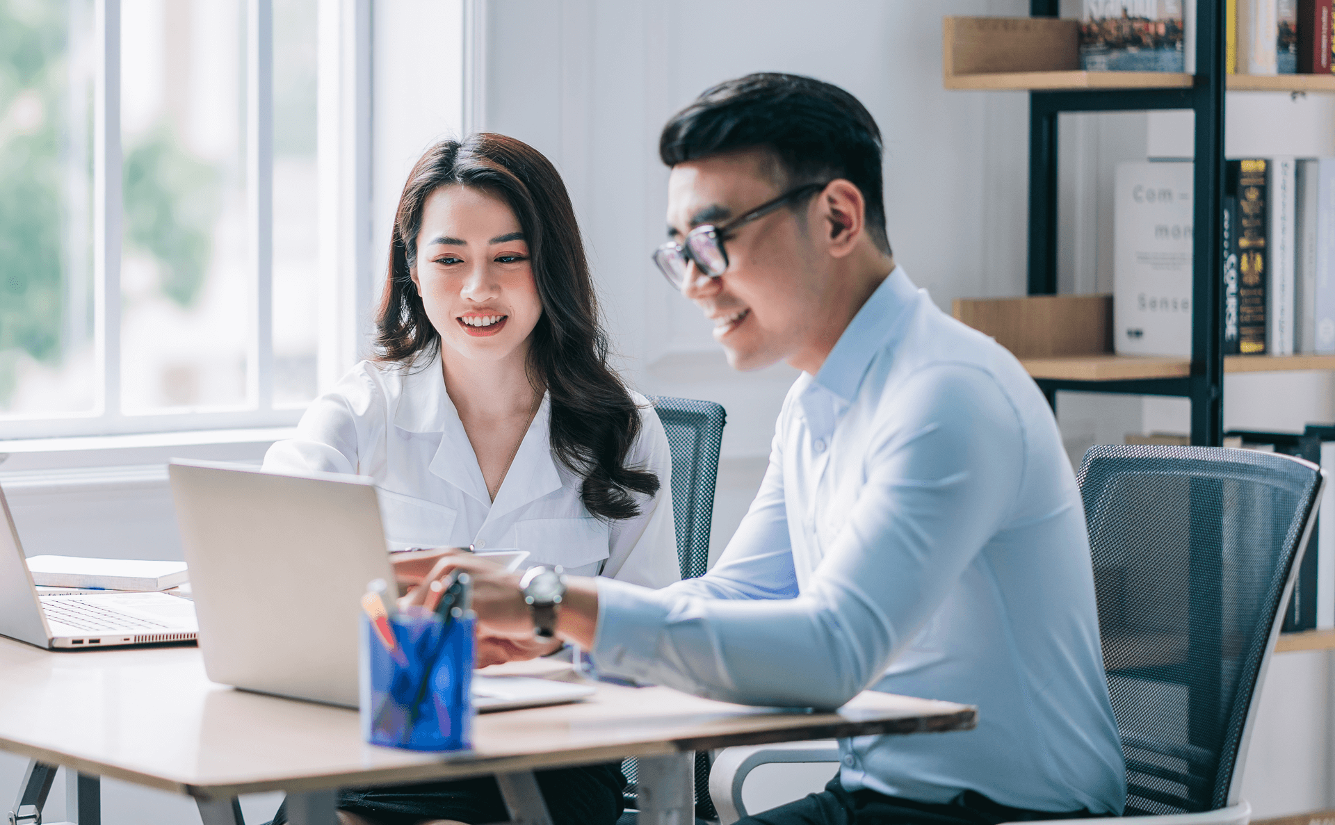 Man and woman sitting at a desk looking at a computer