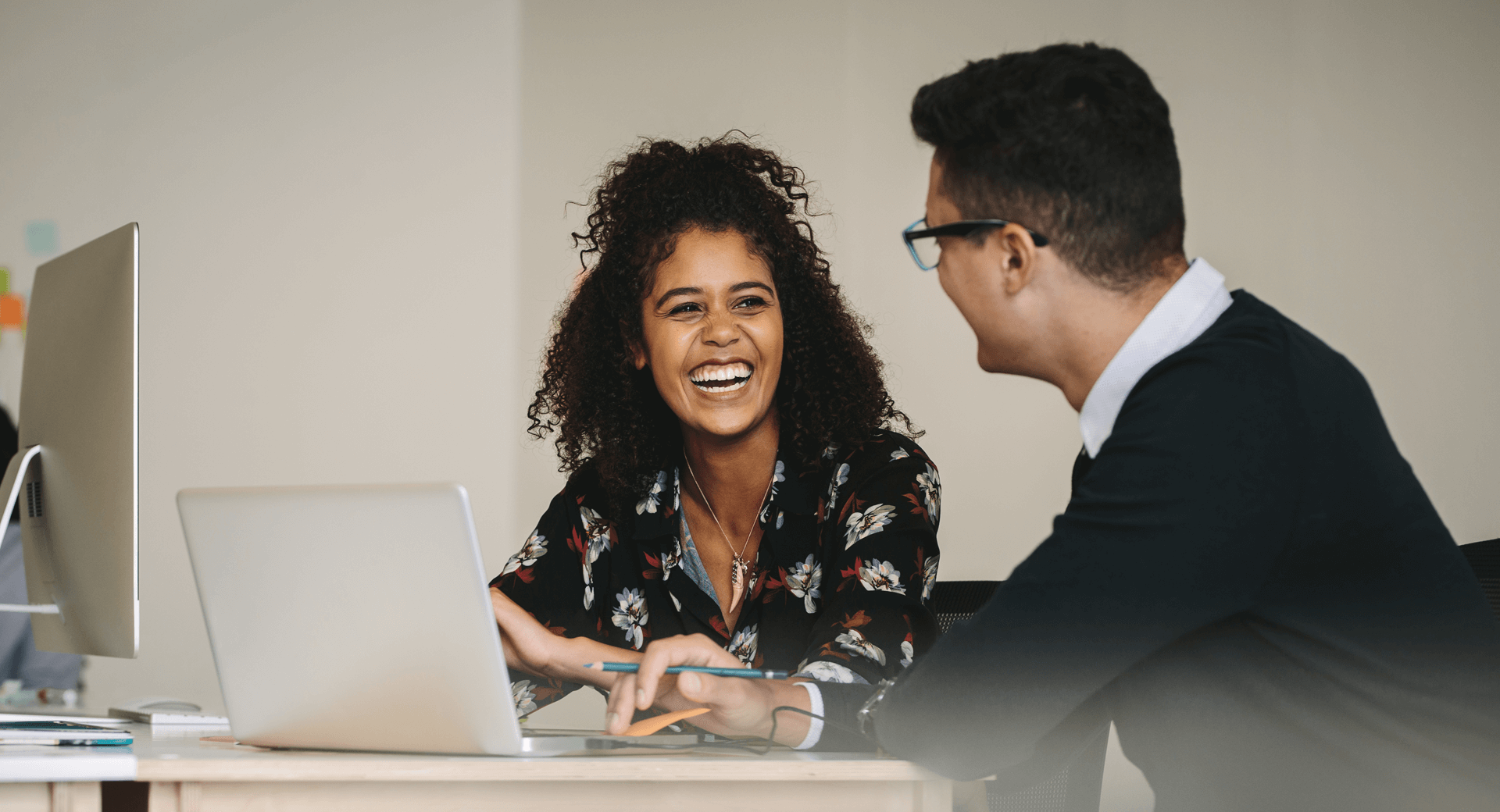 Woman and man sitting at computer talking to each other
