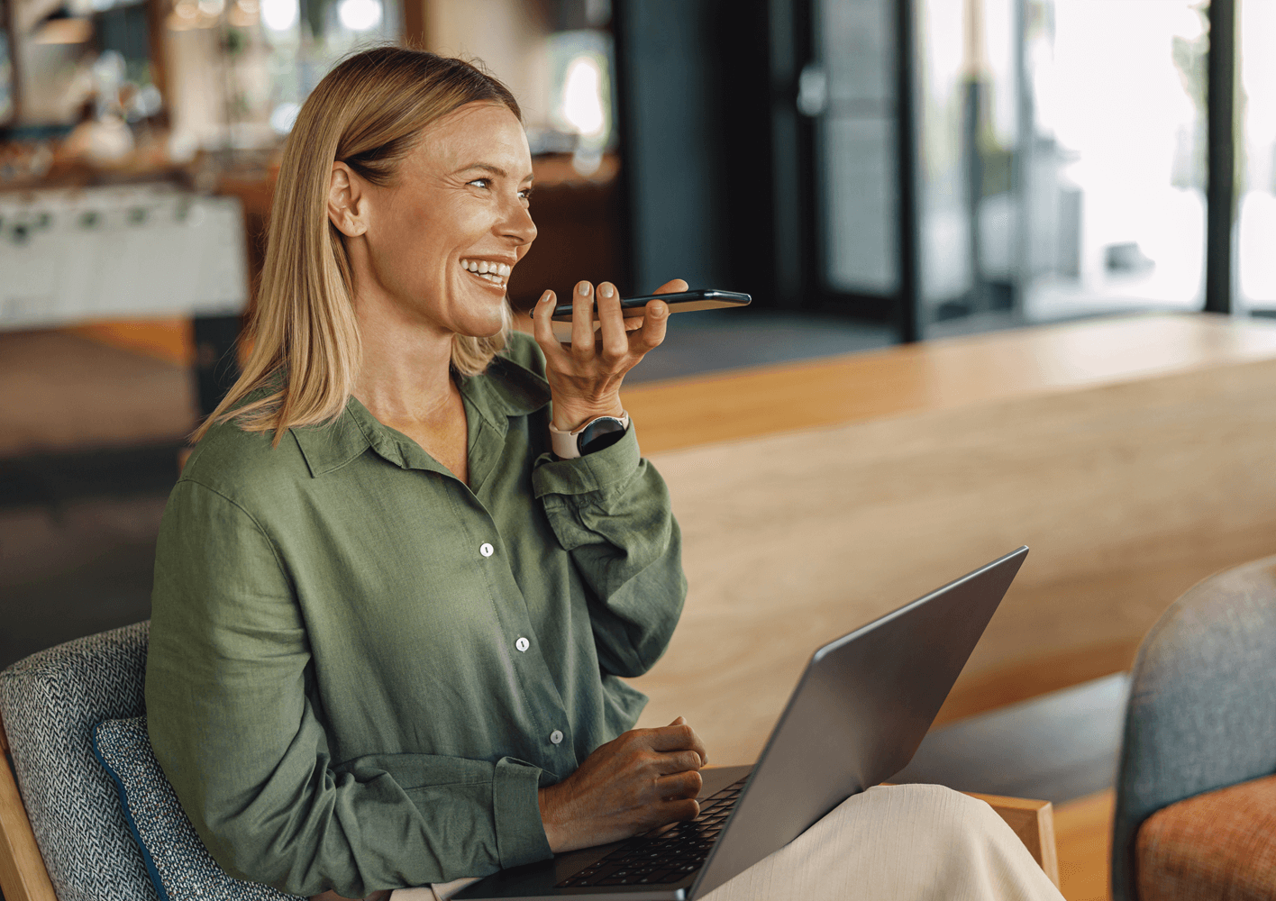Women sitting with laptop on her lap, talking on a mobile phone on loud speaker