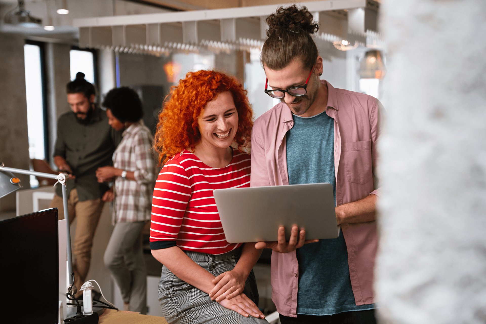 Two people smiling looking at a laptop