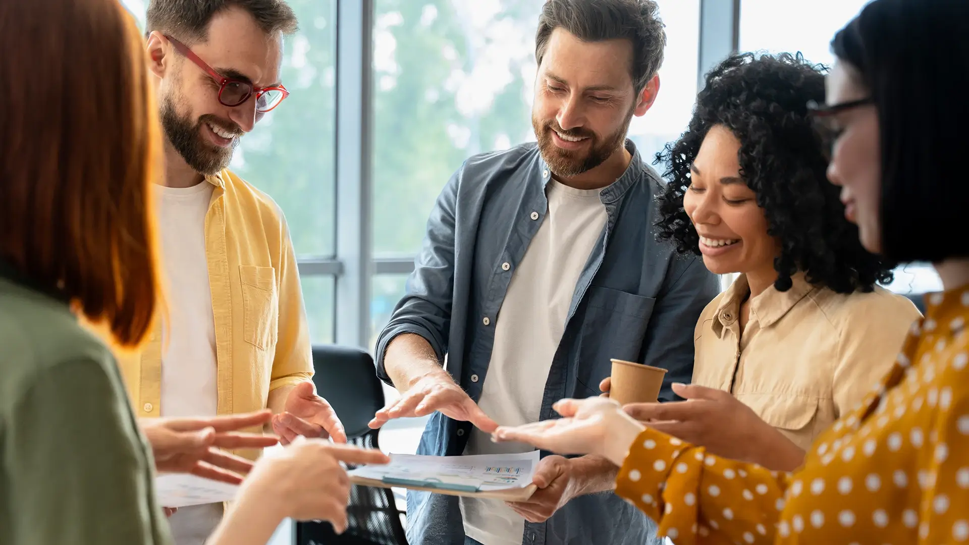 A group of co-workers standing around and talking to each other while looking at data